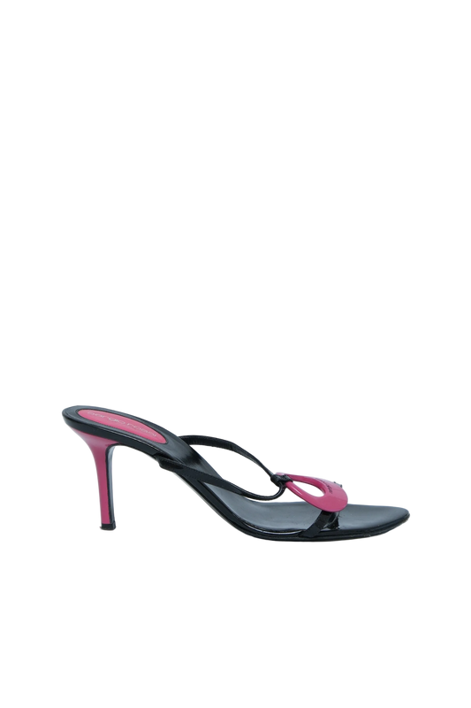 A single black leather high-heeled sandal with a slim stiletto heel and a pink decorative loop detail on the toe strap, shown against a light gray background.