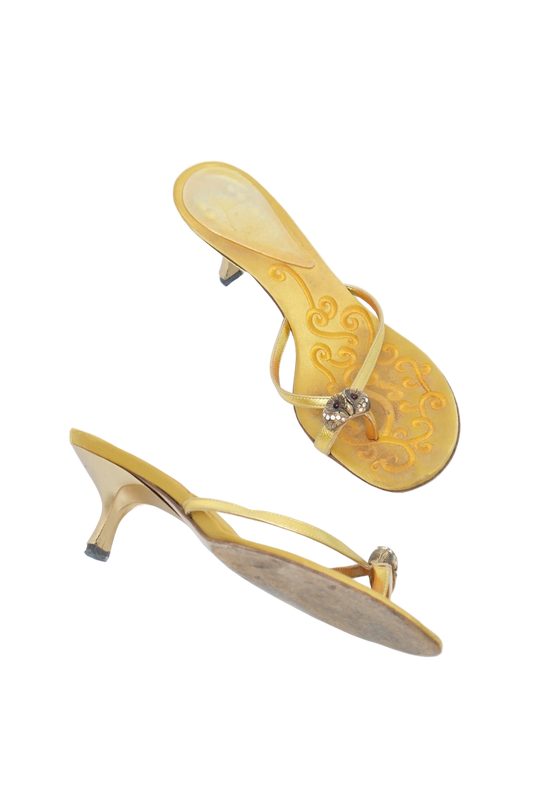 A pair of yellow velvet thong sandals with kitten heels, featuring embossed floral patterns on the soles and a small rhinestone embellishment on the straps, shown on a white background.