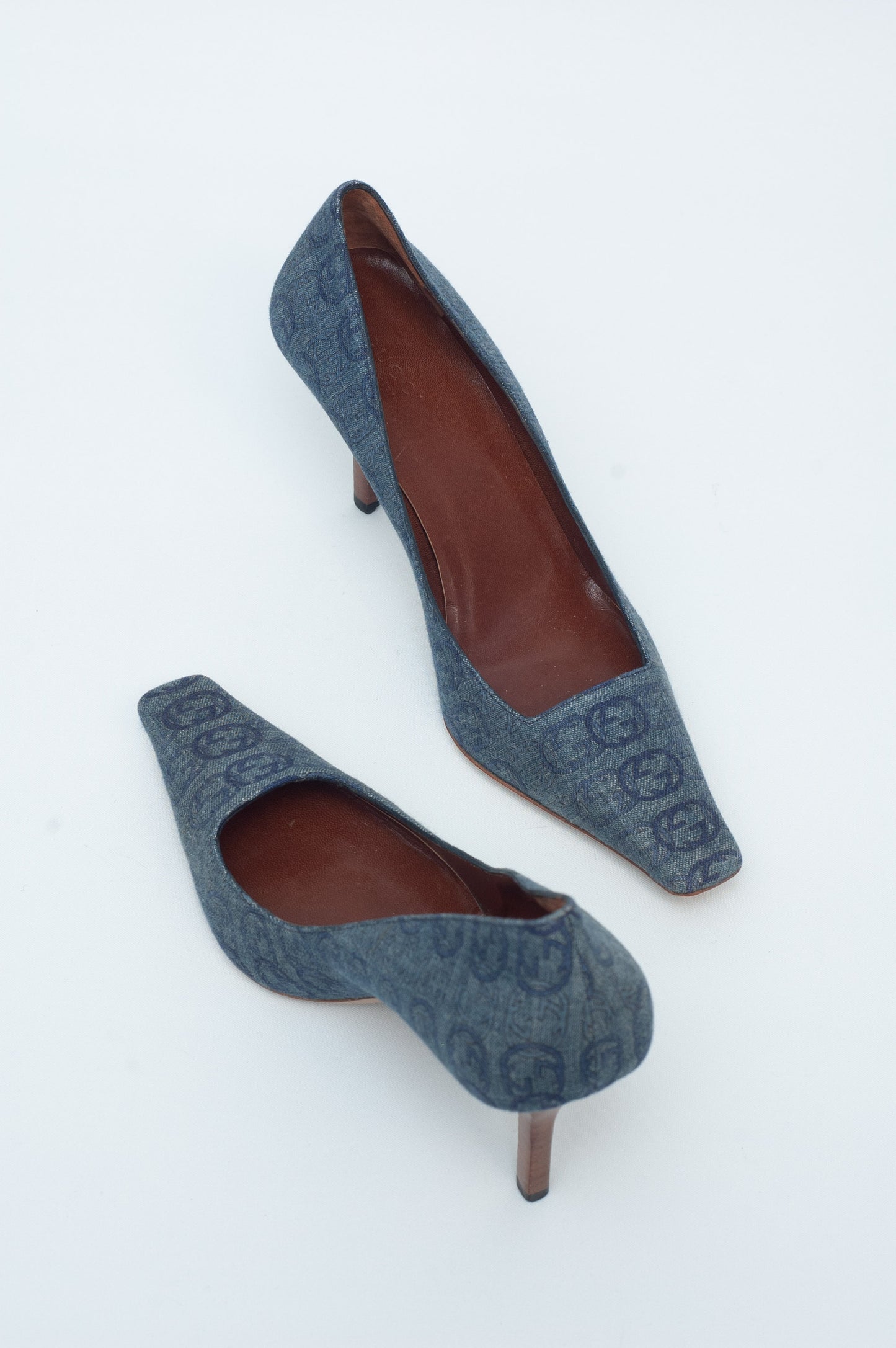 Pair of gray high-heeled shoes with brown soles on a white background