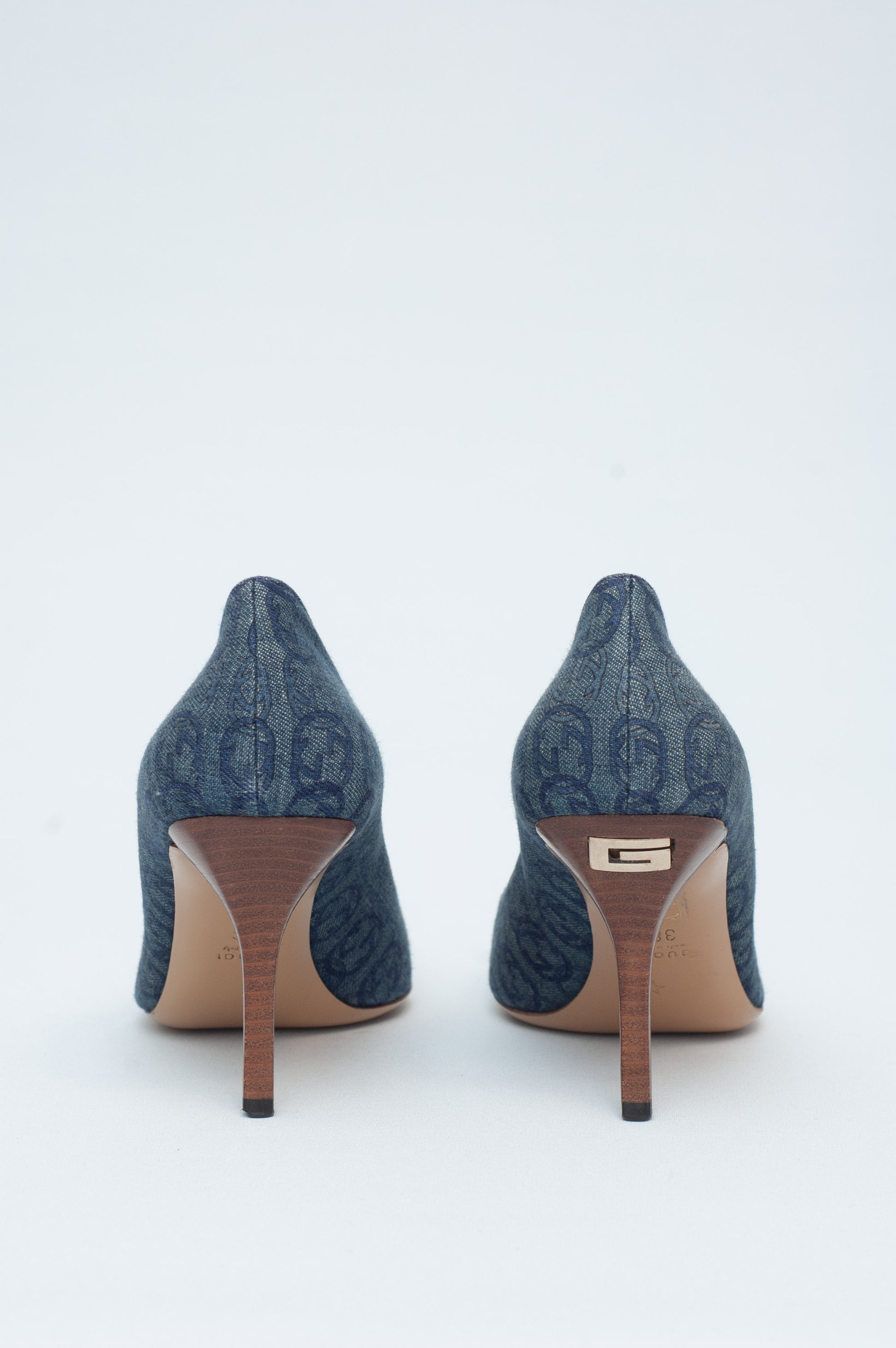 Pair of blue high-heeled shoes with a brand logo on a white background