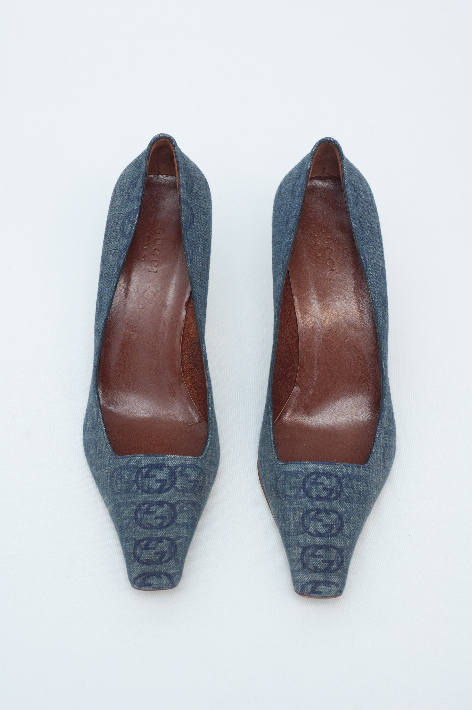 Pair of denim high-heeled shoes with brown soles on a white background