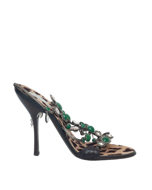 High-heeled shoe with leopard print and green embellishments on a white background