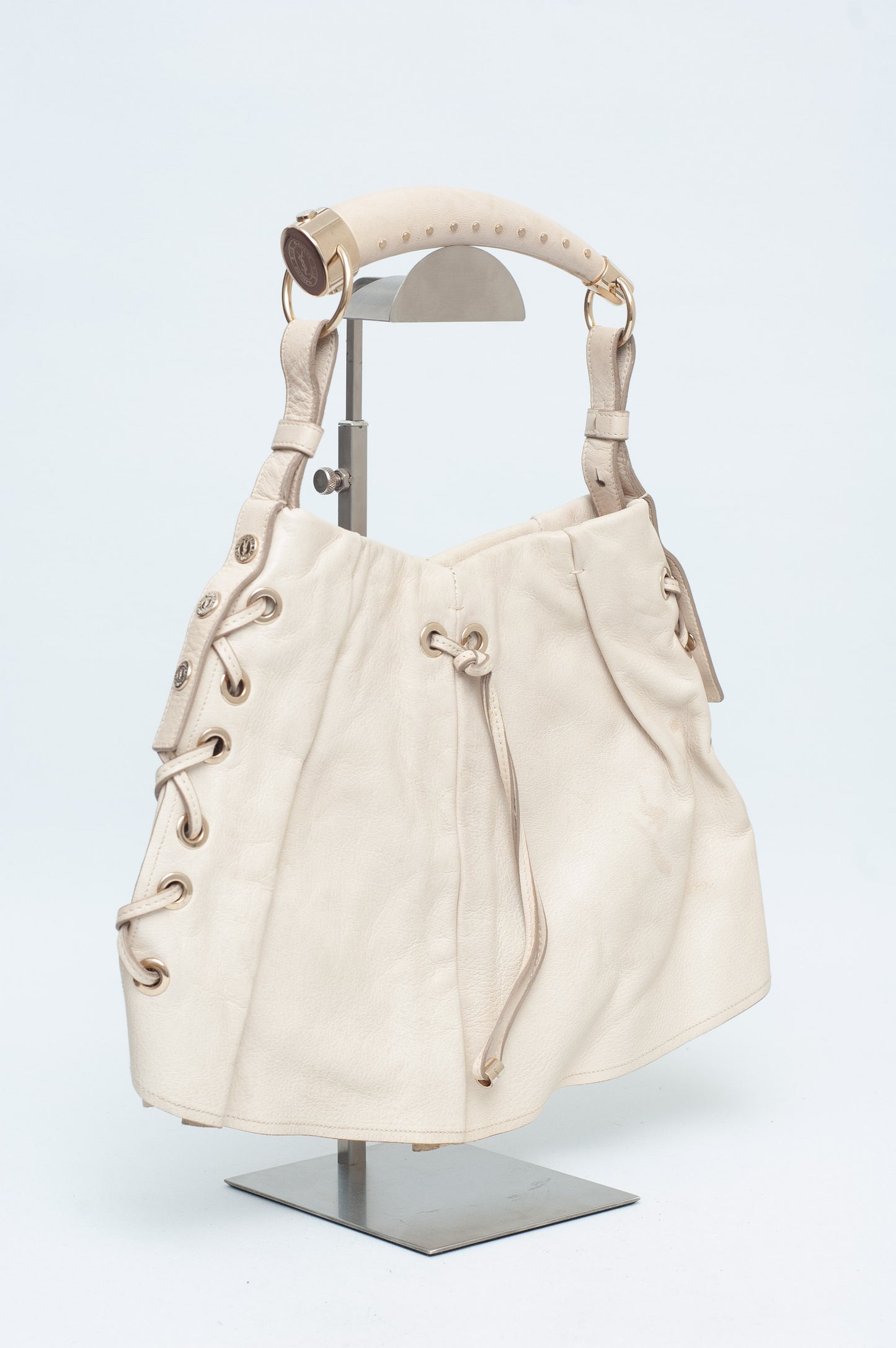 Beige handbag on a mannequin stand against a white background