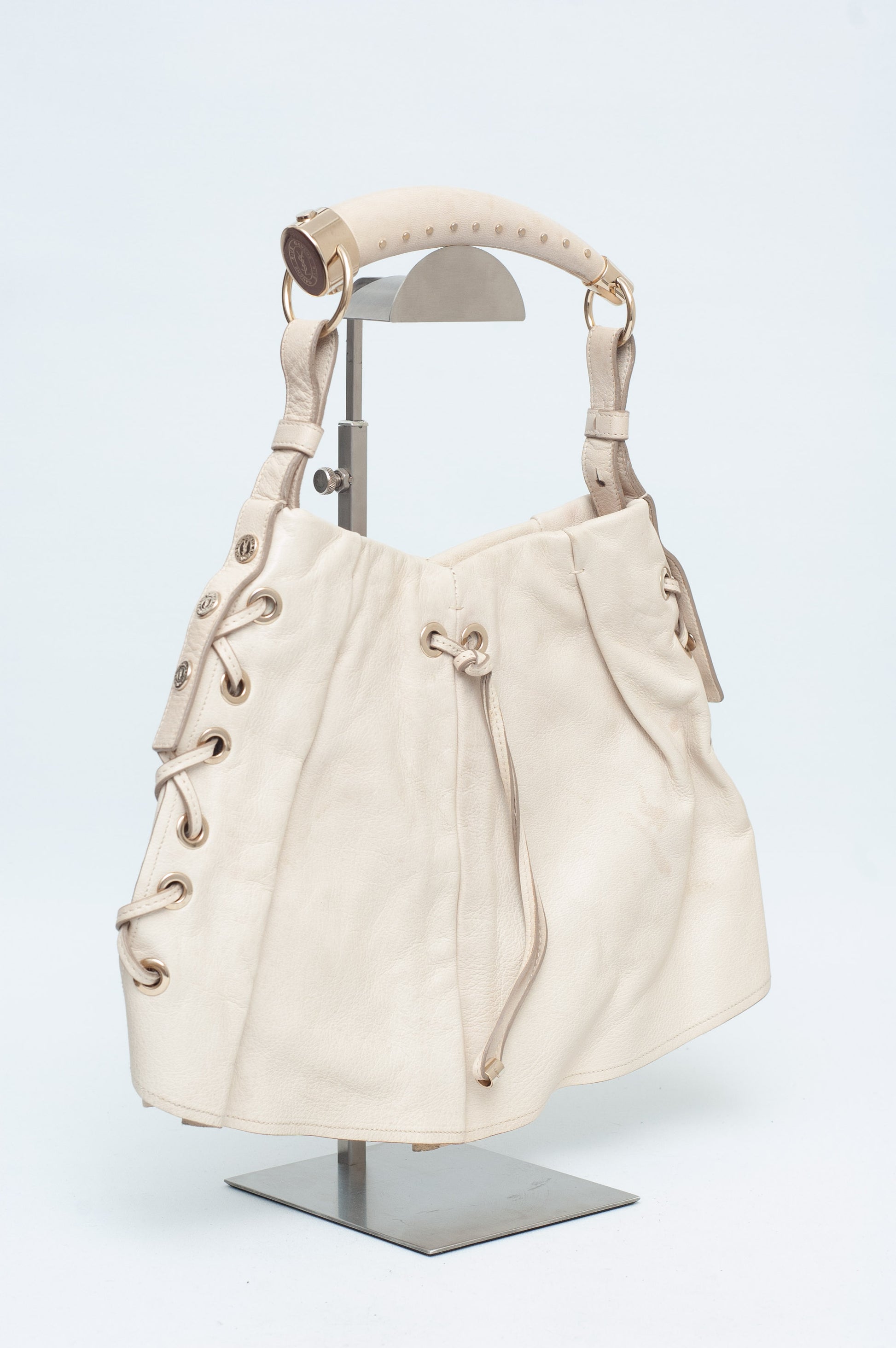 Beige handbag on a mannequin stand against a white background