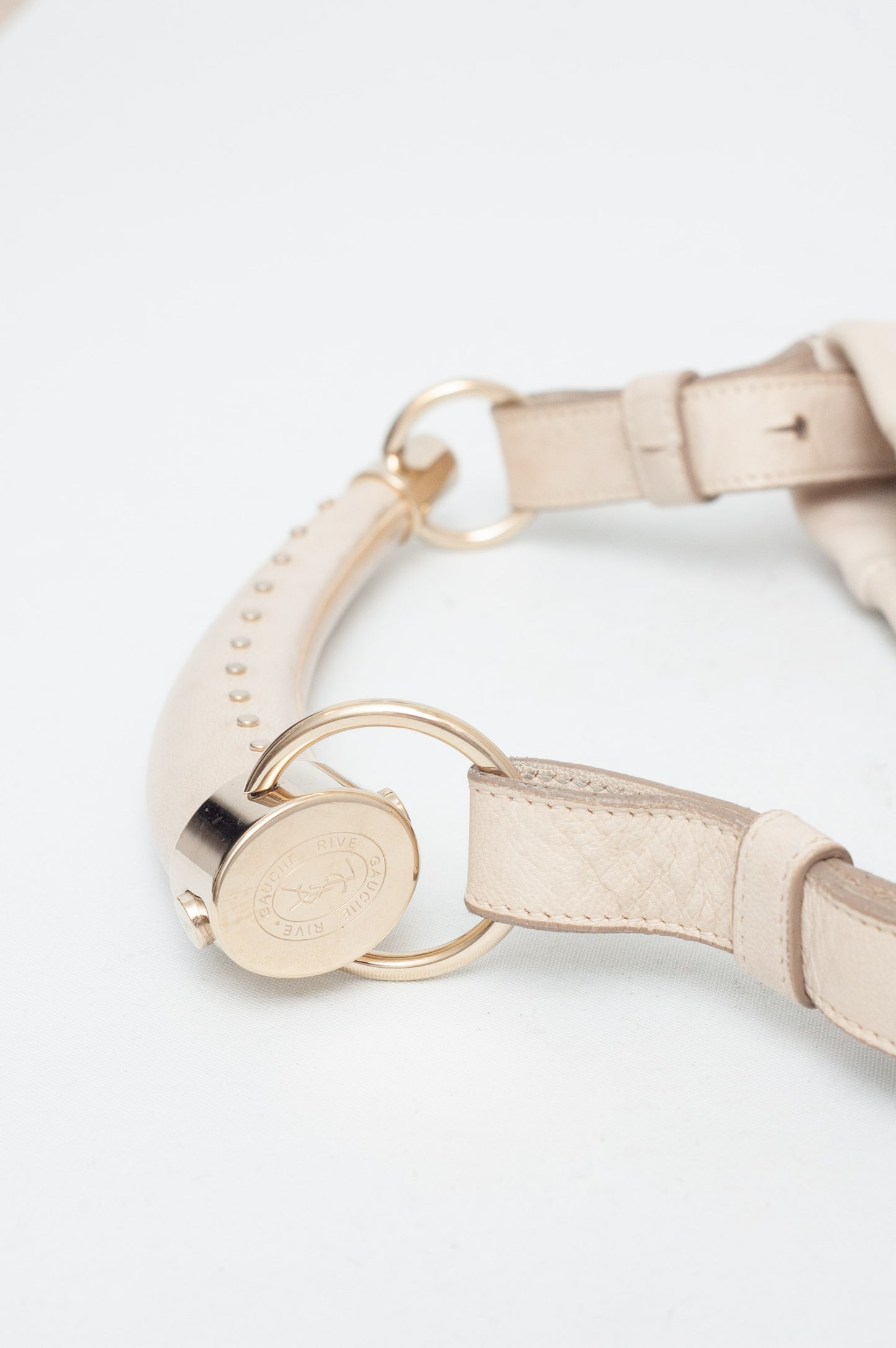 Beige leather belt with gold hardware on a light gray background