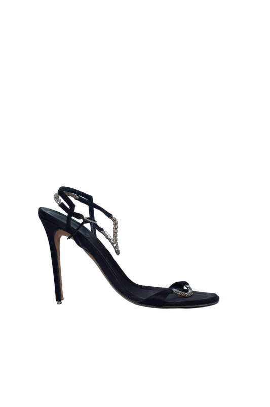Black high-heeled shoe with decorative elements on a light gray background