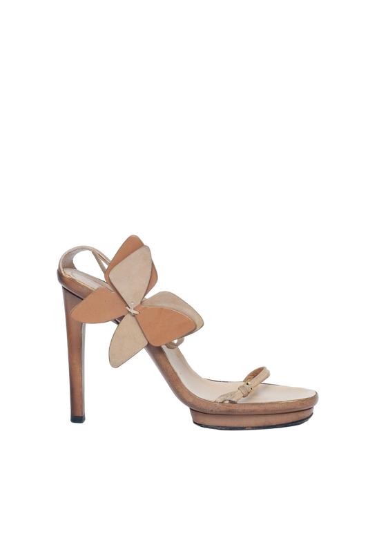 Tan high-heeled sandal with a decorative flower on a white background