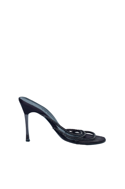 Black high-heeled shoe with braided design on a light blue background